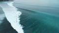 Aerial view of ocean with perfect waves and surfers on Impossibles beach in Bali
