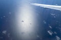 Aerial view of ocean through a plane window. Wing of airplane with blue sky and beauty clouds over the ocean. Aerial sea view