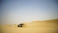 Aerial view on Off-road adventure with SUV in Arabian Desert at sunset with Dubai skyline or cityscape. Desert touring