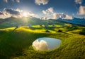 Aerial view of old mountain village, green hills, pond at sunset