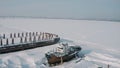 Aerial view of an old pier and a moored rusty ship on a snow covered shore. Clip. Winter landscape of an abandoned pier Royalty Free Stock Photo