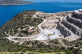 Aerial view of opencast mining quarry with one machinery on the blue sea background. Royalty Free Stock Photo