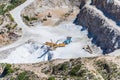 Aerial view of opencast mining quarry with one machinery on the blue sea background. Royalty Free Stock Photo