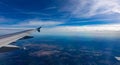 Aerial view out of an airplane window. Cloudy blue sky over countryside.