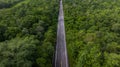 Aerial view over forest road with asphalt road and forest, Road in the middle of the forest up to mountain, Countryside road