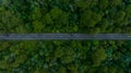 Aerial view over forest road with asphalt road and forest, Road in the middle of the forest up to mountain, Countryside road