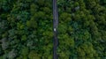 Aerial view over forest road with asphalt road and forest, Road in the middle of the forest up to mountain, Countryside road