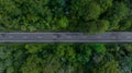 Aerial view over forest road with asphalt road and forest, Road in the middle of the forest up to mountain, Countryside road