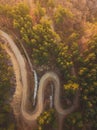 Aerial view over mountain road inside forest during sunrise