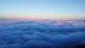 Aerial view over the mountains with sea of fog during morning sunrise in blue sky. Sea of clouds around mountain peaks at sunrise Royalty Free Stock Photo