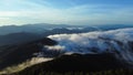 Aerial view over the mountains with sea of fog during morning sunrise in blue sky. Sea of clouds around mountain peaks at sunrise Royalty Free Stock Photo