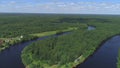 Aerial view over river and green valley near countryside houses. Shot. Beautiful narrow river curving through fields