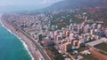 Aerial view over sandy beach and coast of the southern city on a sunny day. Clip. Summer city located by the sea.