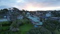 Aerial view over the shore and rooves of seaside houses at Murrays bay, Auckland, during the sunset