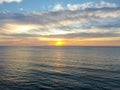 Aerial view of Pacific ocean colorful sunset with sun reflection on the ocean and deep clouded sky. Royalty Free Stock Photo