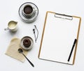 Aerial view of paper clipboard with coffee cup and cake