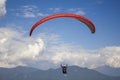 Aerial view of paraglider with a red parachute in a blue sky with white clouds over green mountainsaerial view of paraglider with