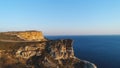 Aerial view of people standing on a large cliff against blue clear sky and blue sea water. Shot. Beautiful view from