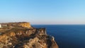 Aerial view of people standing on a large cliff against blue clear sky and blue sea water. Shot. Beautiful view from