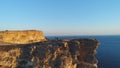 Aerial view of people standing on a large cliff against blue clear sky and blue sea water. Shot. Beautiful view from