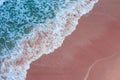 Aerial view of pink beach and blue ocean wave.