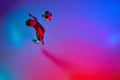 Aerial view of playing little boy during training with football ball in gradient red-blue neon light. Concept of action