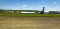 Aerial View of a Plowed Field with a Barn, Silos and Farm House in View