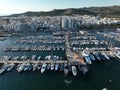 Aerial view of pontoons full of boats and sailboats in the marina, facing the city.
