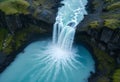 Aerial view of a powerful waterfall cascading into a circular turquoise pool surrounded by cliffs.