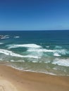 Aerial view of sandy beach with clear blue ocean and blue sky in the background