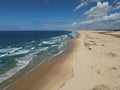 Aerial view of sandy beach with clear blue ocean and blue sky in the background