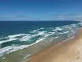 Aerial view of sandy beach with clear blue ocean and blue sky in the background