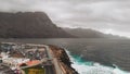 Aerial view of the promenade and coastal stones in the port city of Agaete. Giant misty rocks hanging over the dark