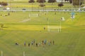 Aerial view of public sports park with children engaged in football game on grass stadium at sunset. Active way of life Royalty Free Stock Photo