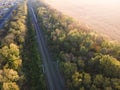Aerial view railroad and train in autumn forest in foggy sunrise. Top view rural railway