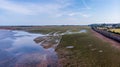 An aerial view of a railway track dam along a sandy beach and road under a majestic cloudy blue sky Royalty Free Stock Photo