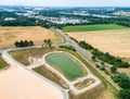 Aerial view of a rain retention basin at the edge of a new development, taken oblique