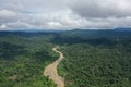 Aerial view of the rainforest with a large brown river meandering through the landscape and shadows of clouds over the rainforest