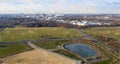 Aerial view of a rainwater retention basin with roads and a large meadow area and an industrial city in the background