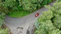 Aerial view of red car driving on country road in forest. Royalty Free Stock Photo