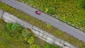 Aerial view of red car driving on country road in forest. Royalty Free Stock Photo