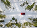 Aerial view of red car driving through the white snow winter forest on country road in Finland, Lapland Royalty Free Stock Photo