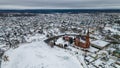 Aerial view of red catholic church and small town in winter. Idyllic landscape with church, houses, river and riverbank Royalty Free Stock Photo