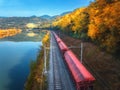 Aerial view of red freight train moving near river in mountains Royalty Free Stock Photo
