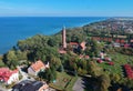 Aerial view at red lighthouse, at baltic sea coast with forest and buildings.