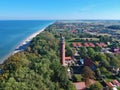 Aerial view at red lighthouse, at baltic sea coast with forest and buildings.