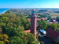 Aerial view at red lighthouse, at baltic sea coast with forest and buildings.