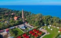 Aerial view at red lighthouse, at baltic sea coast with forest and buildings.