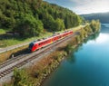 Aerial view of red modern high speed train moving near river Royalty Free Stock Photo