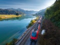 Aerial view of red speed train moving near river in mountains Royalty Free Stock Photo
